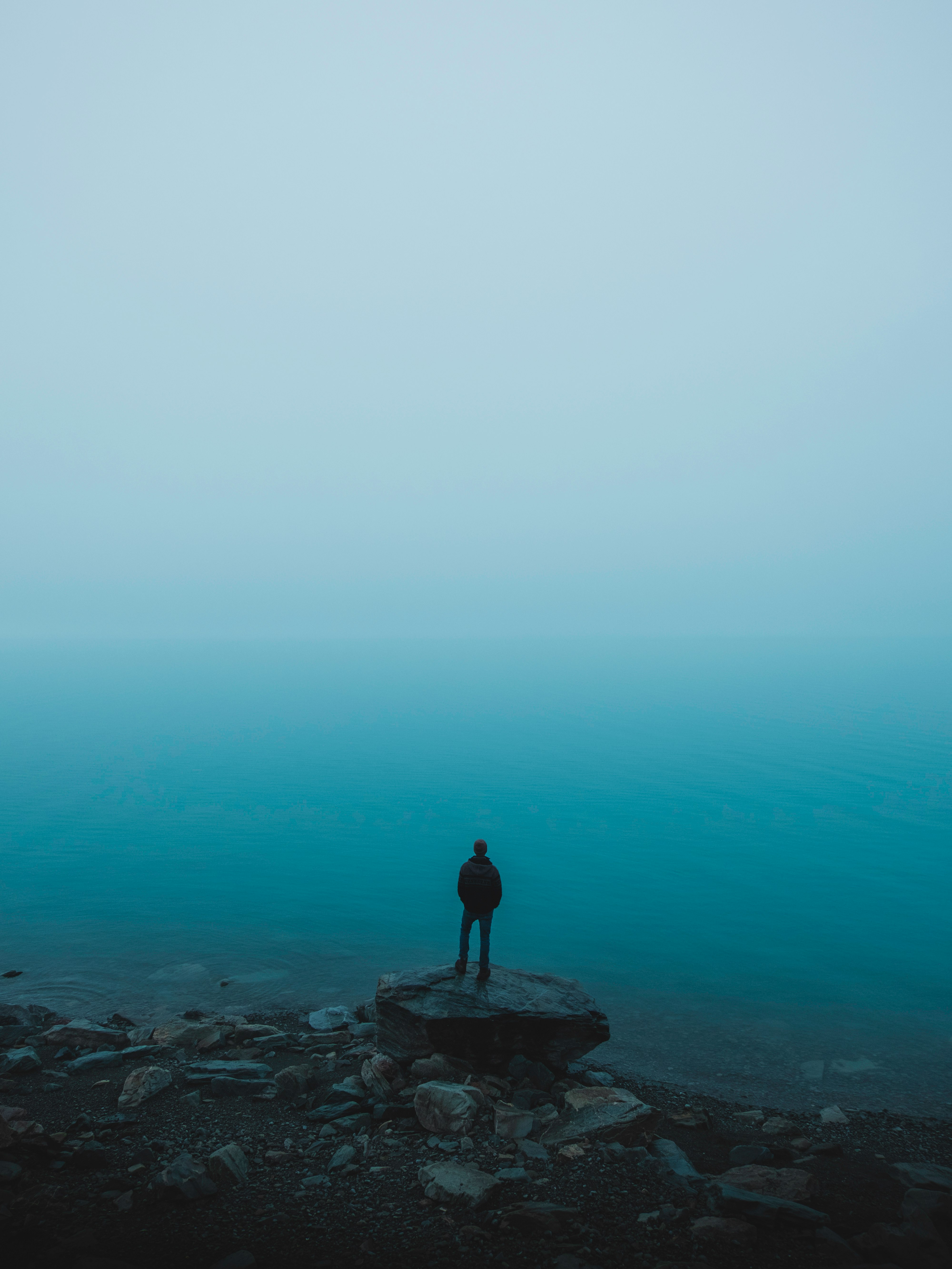 man standing on rock near body of water